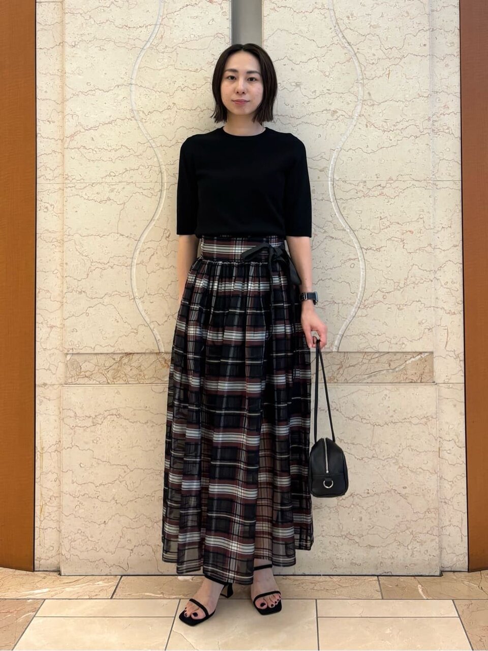 黒ニットとチェックスカートを着た女性