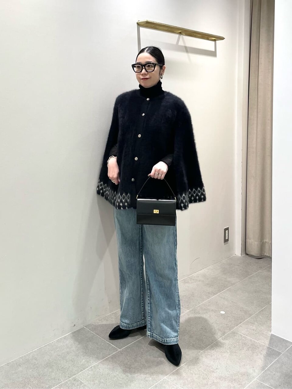 ケープと黒ニットを着た女性