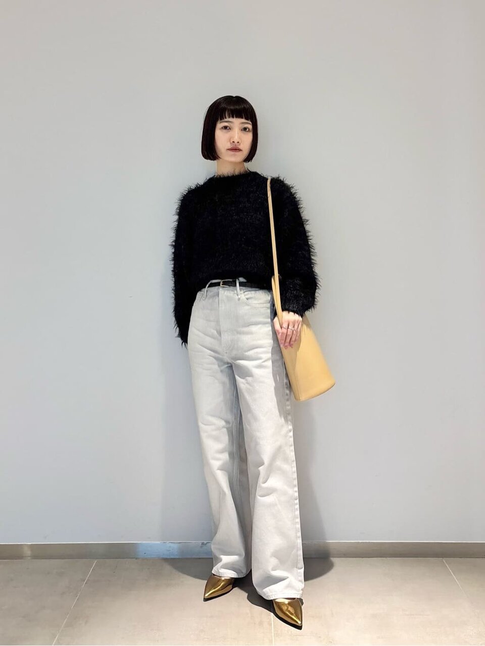 黒ニットとホワイトデニムを着た女性