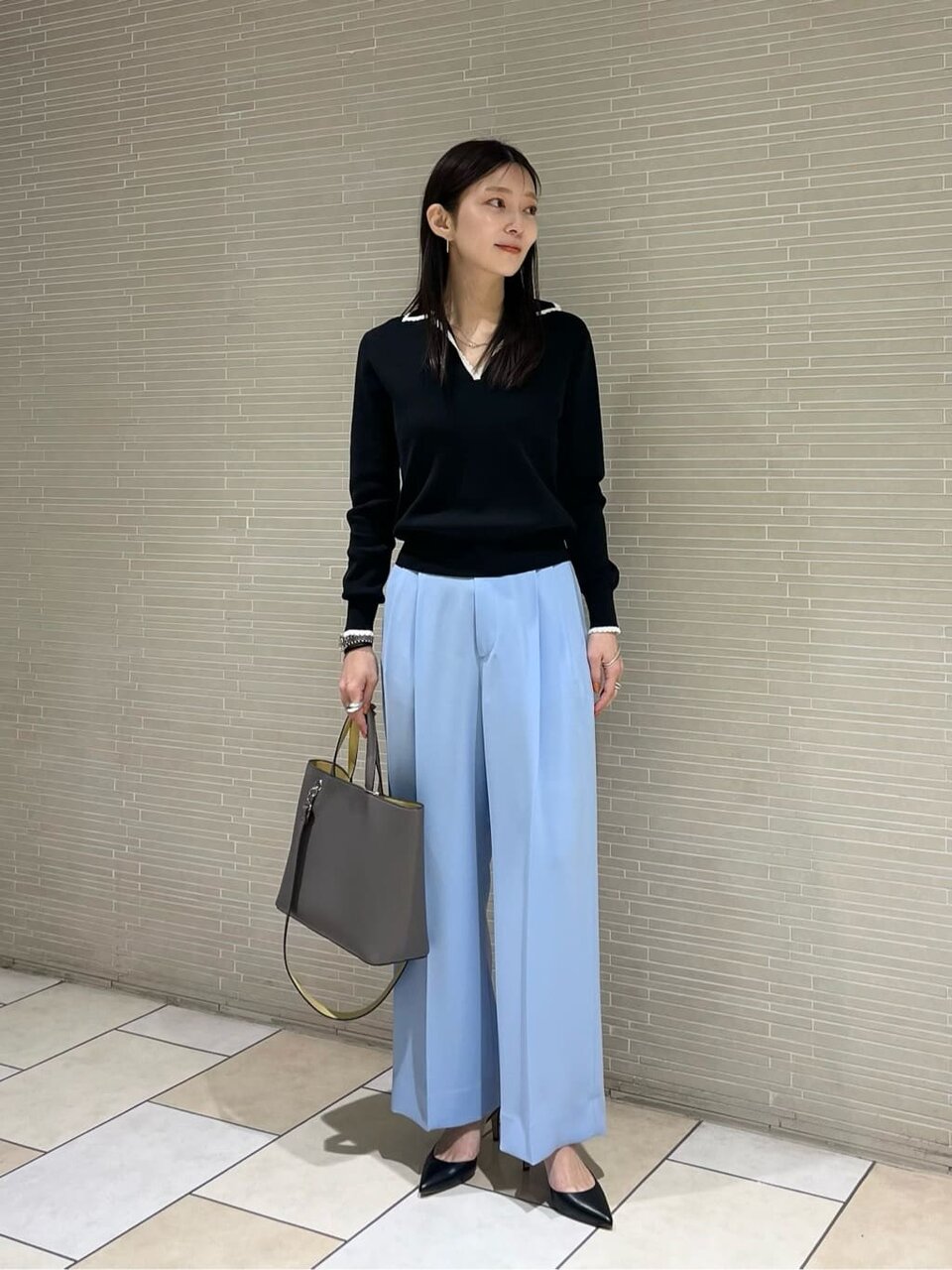 黒ニットとブルーパンツの女性