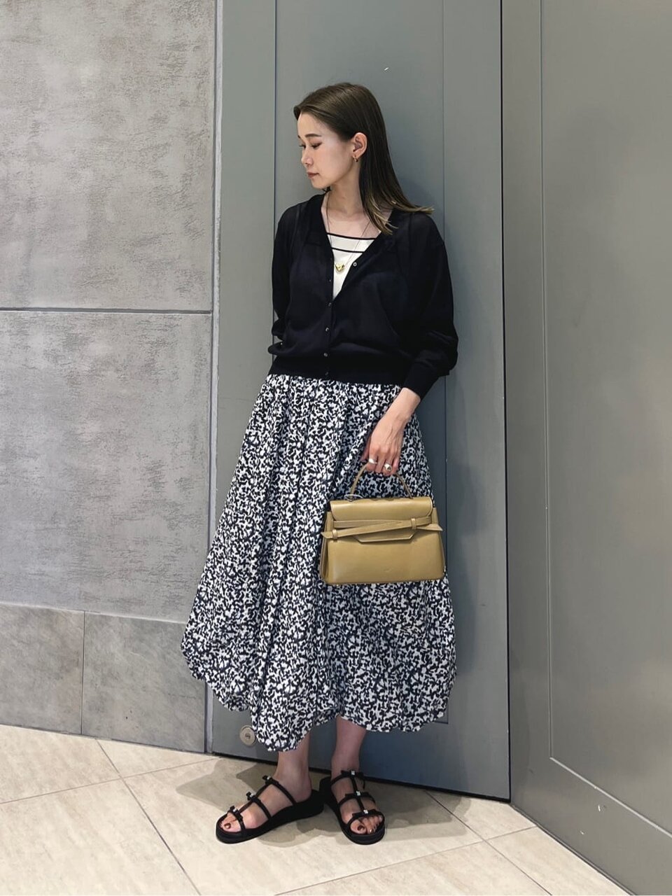 黒ニットと花柄スカートを着た女性