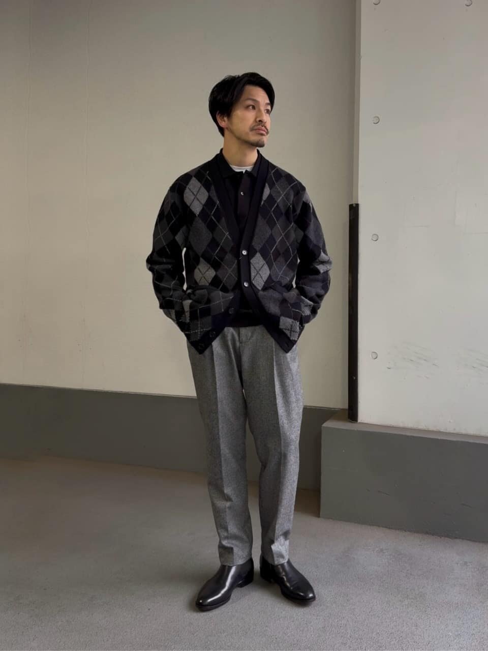 アーガイルカーディガンとスラックスを着た男性