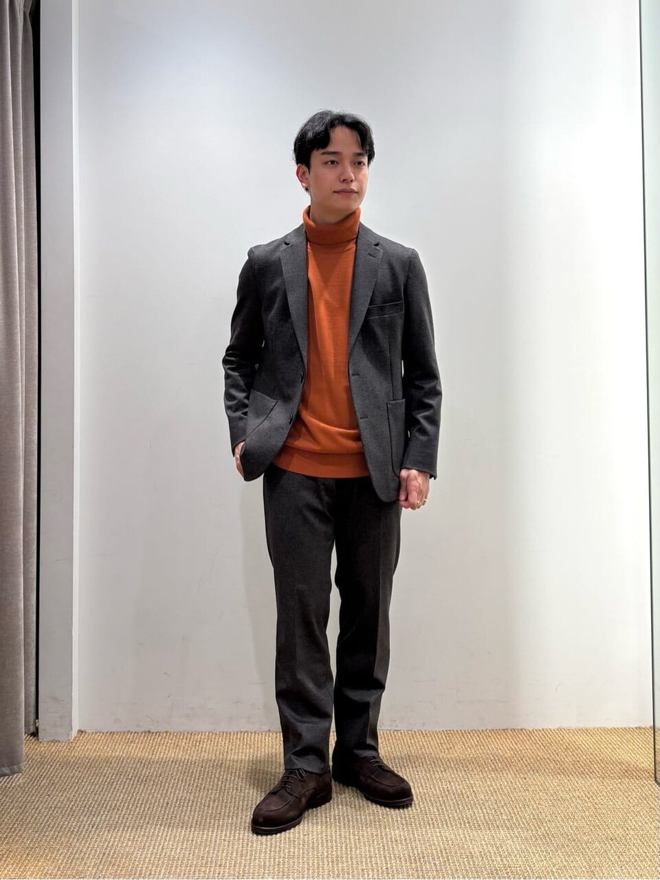 オレンジのニットとジャケットを着た男性