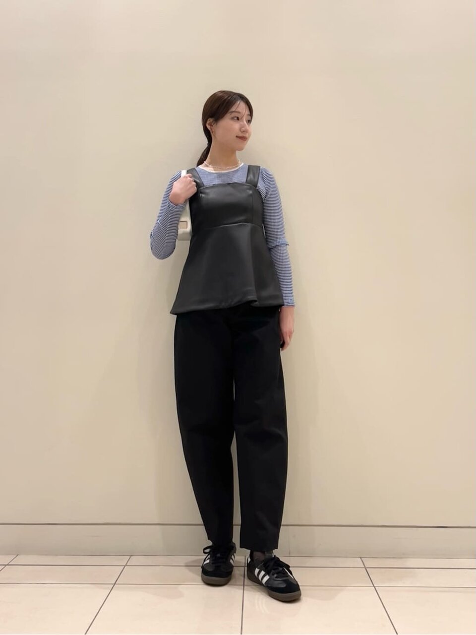 レザーライクビスチェとスニーカーを身につけた女性