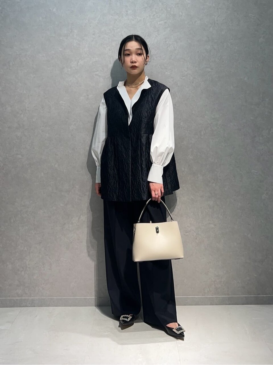 白シャツとジャガードベストの女性