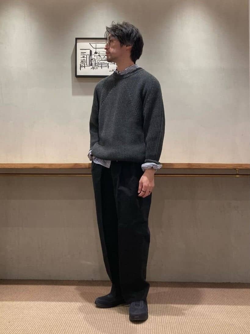 グレーのニットにストライプ柄シャツをレイヤードしたコーデ