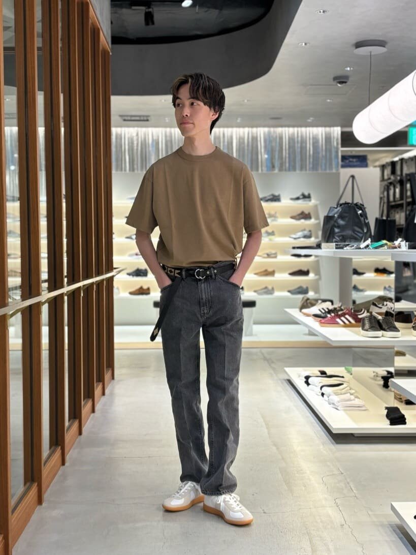 オリーブカラーのTシャツをタックインした男性