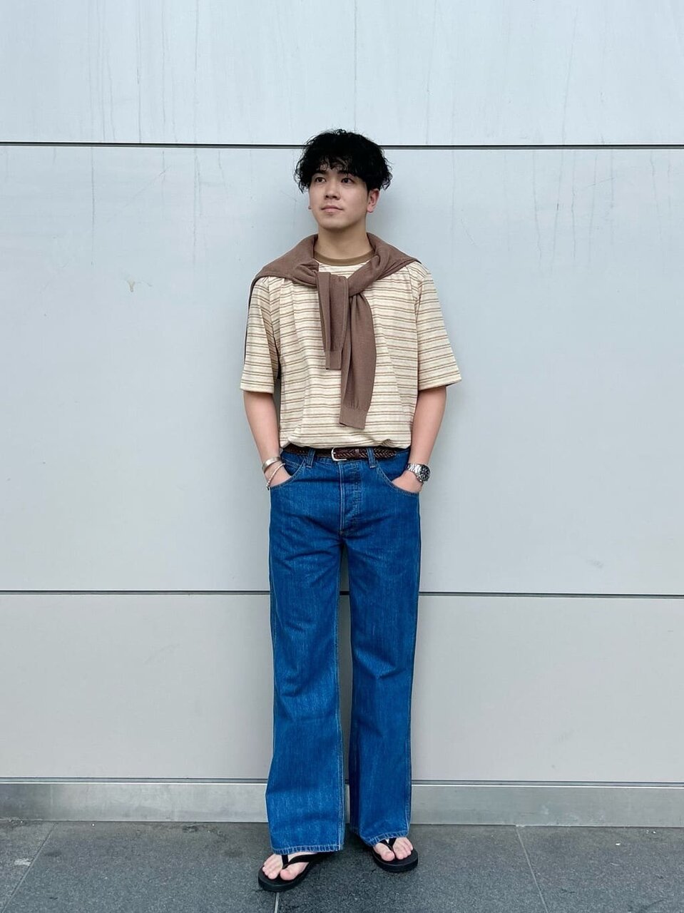 ブラウンのトップスをタックインした男性