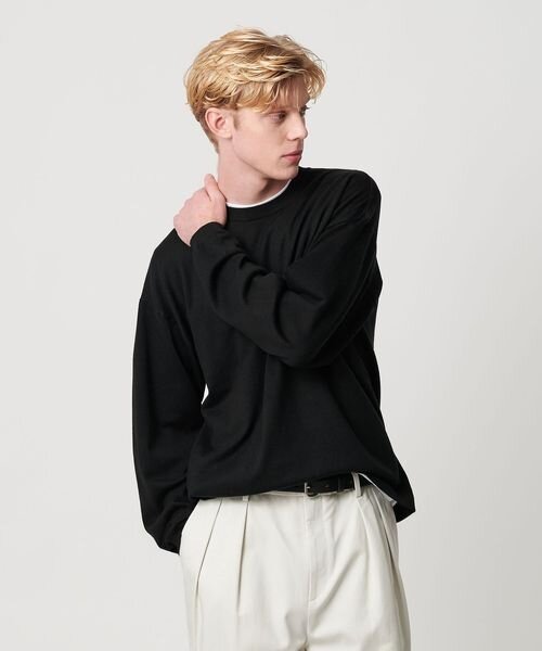 黒ニット×白のパンツの男性