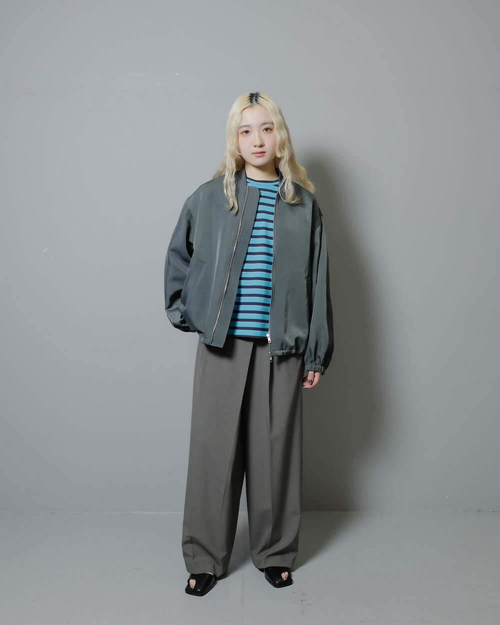 マルチボーダーTシャツとダークトーンアイテムを身に付けた女性
