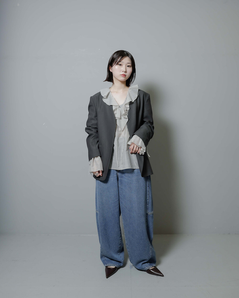 フリルブラウスとノーカラージャケットを着た女性