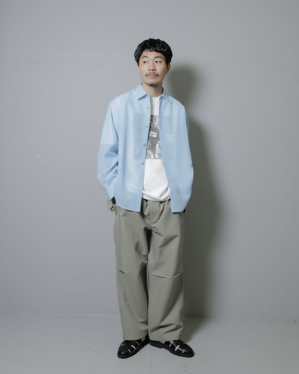 フォトTシャツとブルーシャツを重ね着した男性