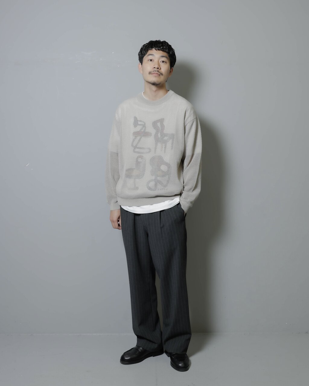 グラフィックTシャツとシアーニットを重ね着したコーデ