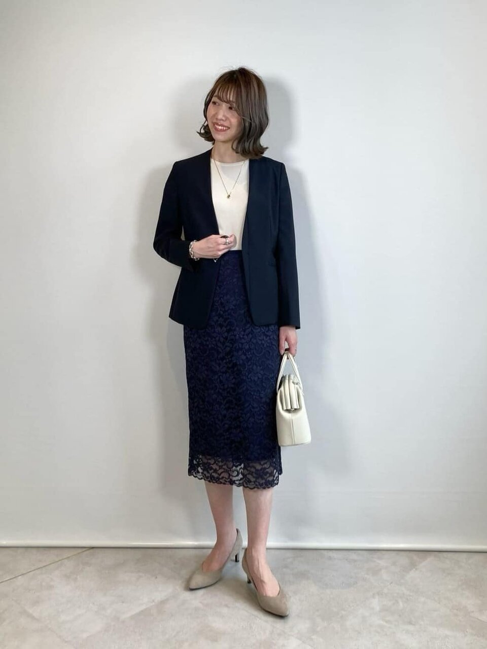 ネイビーのレーススカートとネイビーのジャケットコーデの女性