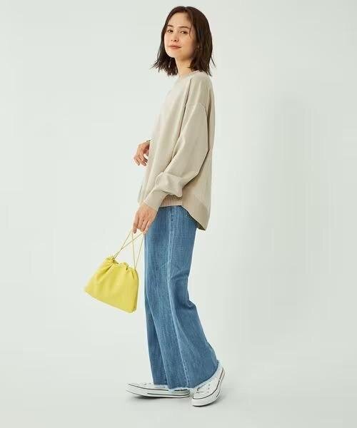 ベージュのニットとデニムパンツを着た女性