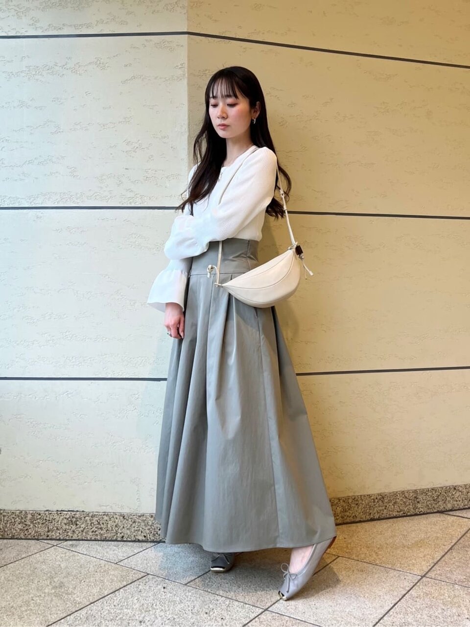 ホワイトニットとグレーのフレアスカートを着た女性