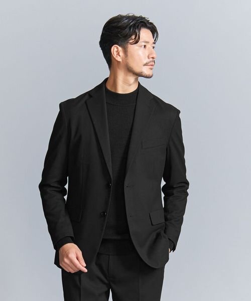 黒ニットと黒ジャケットを着た男性