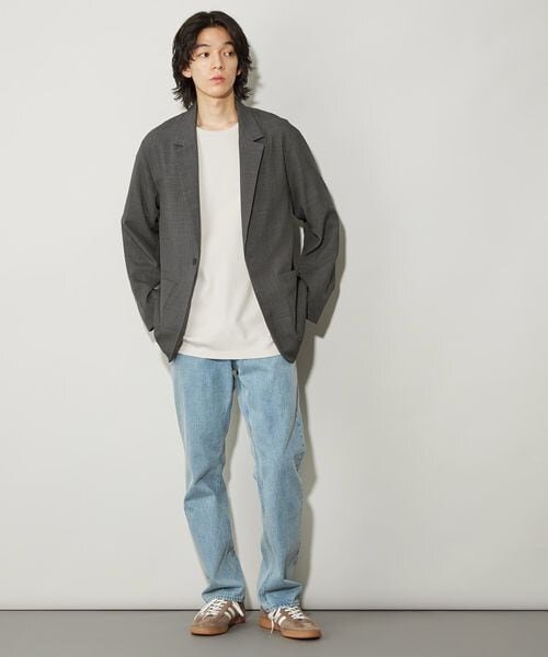 ジャケットとデニムパンツを来た男性