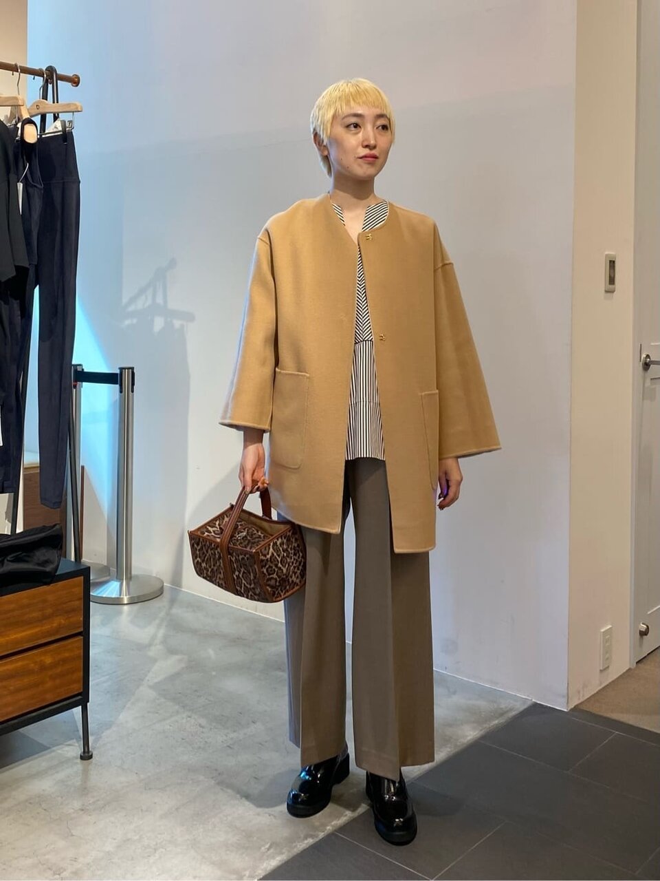 キャメルのノーカラーコートとワイドパンツを着た女性