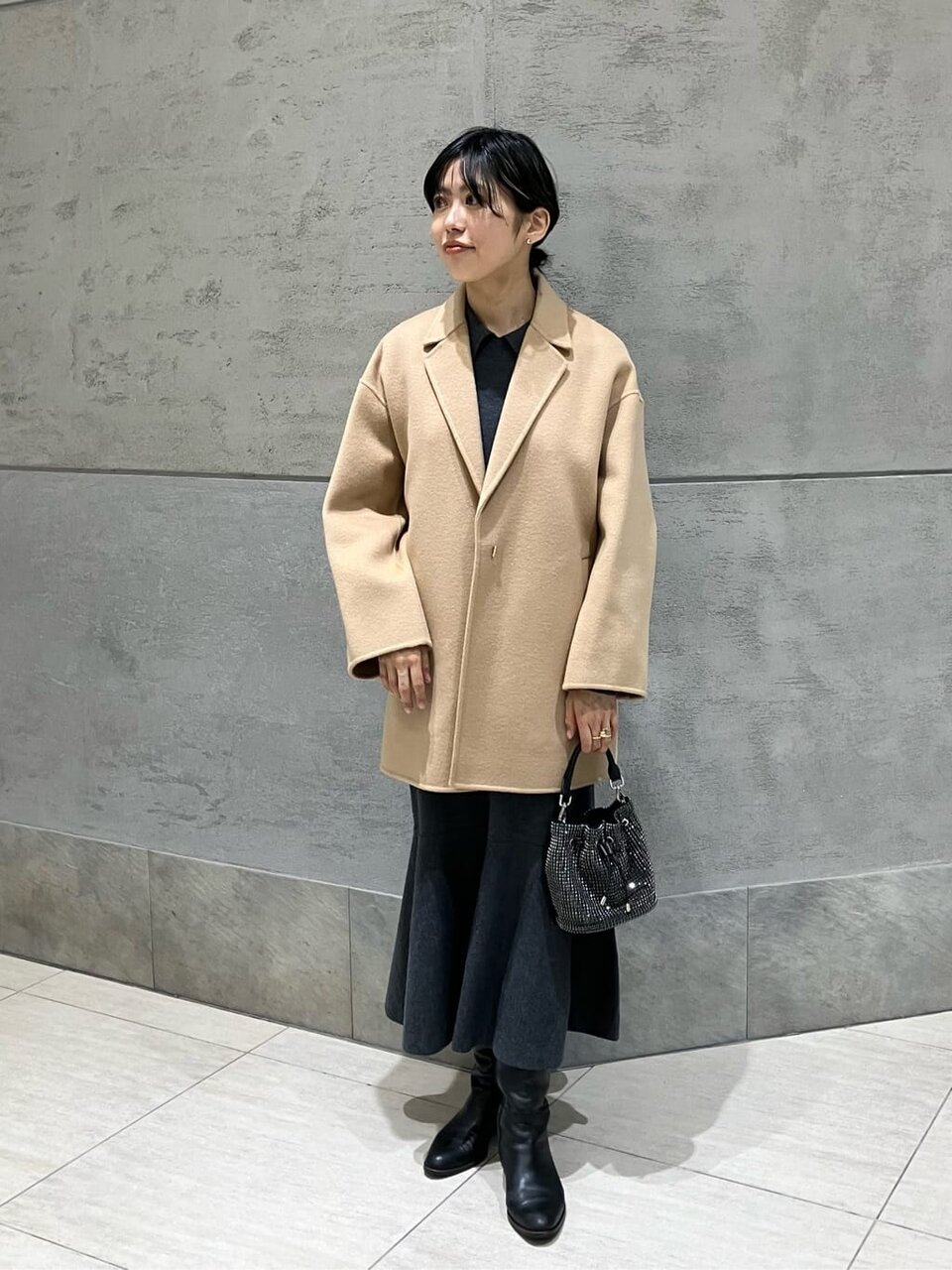 ベージュのコートとワンピースの女性