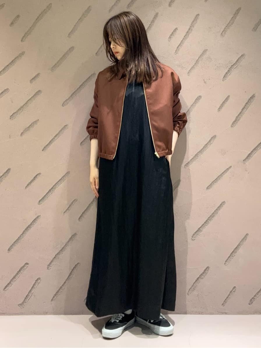 ブラウンのジップブルゾンとワンピースを着た女性