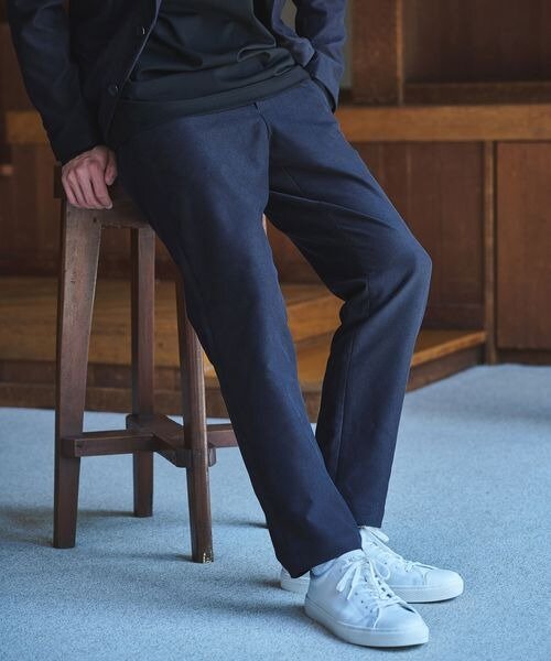 テーパードパンツをはいた男性の足