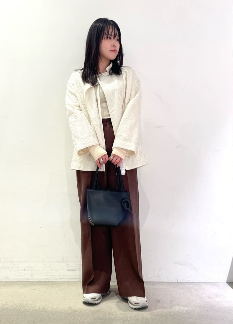 茶色のパンツ×白のジャケットコーデの女性