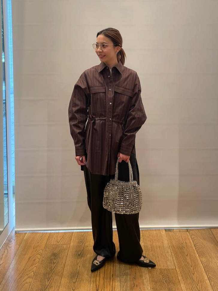 茶色のシャツ×黒のパンツコーデの女性