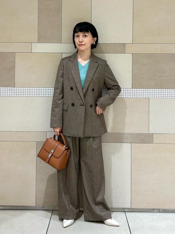 茶色のセットアップとライムグリーンのニットのコーデ