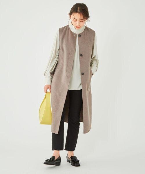 グレージュのロングジレを着た女性