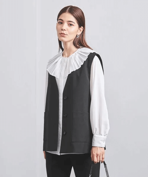フリルブラウスにジレを羽織った女性