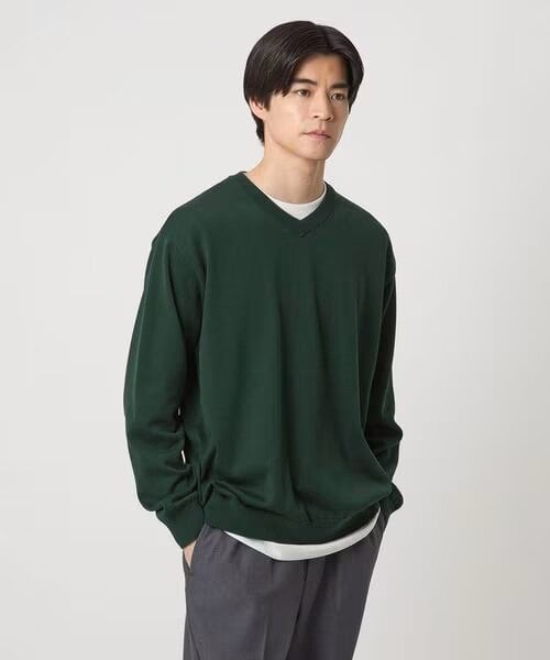 ダークグリーンのVネックニットを着ている男性