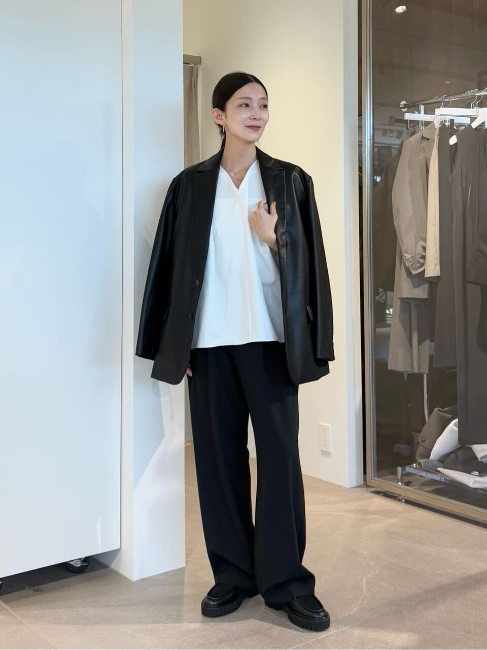 レザージャケットとタックパンツをあわせた女性