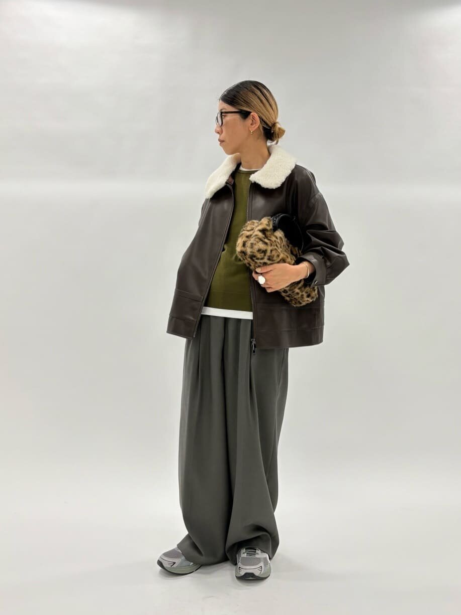 レザージャケットにワイドパンツをあわせた女性