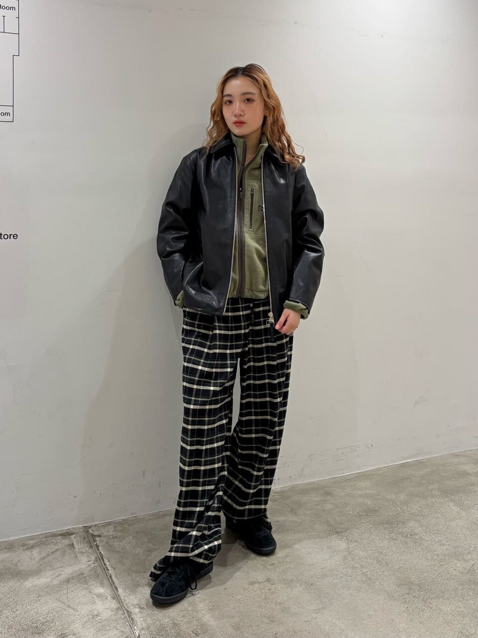 レザージャケットにチェック柄パンツをあわせた女性