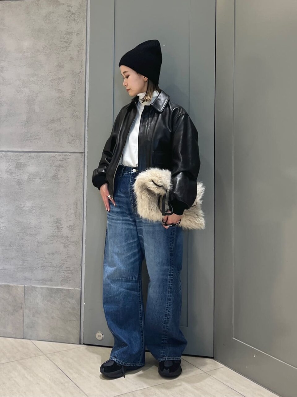 黒のレザージャケットにデニムパンツをあわせた女性