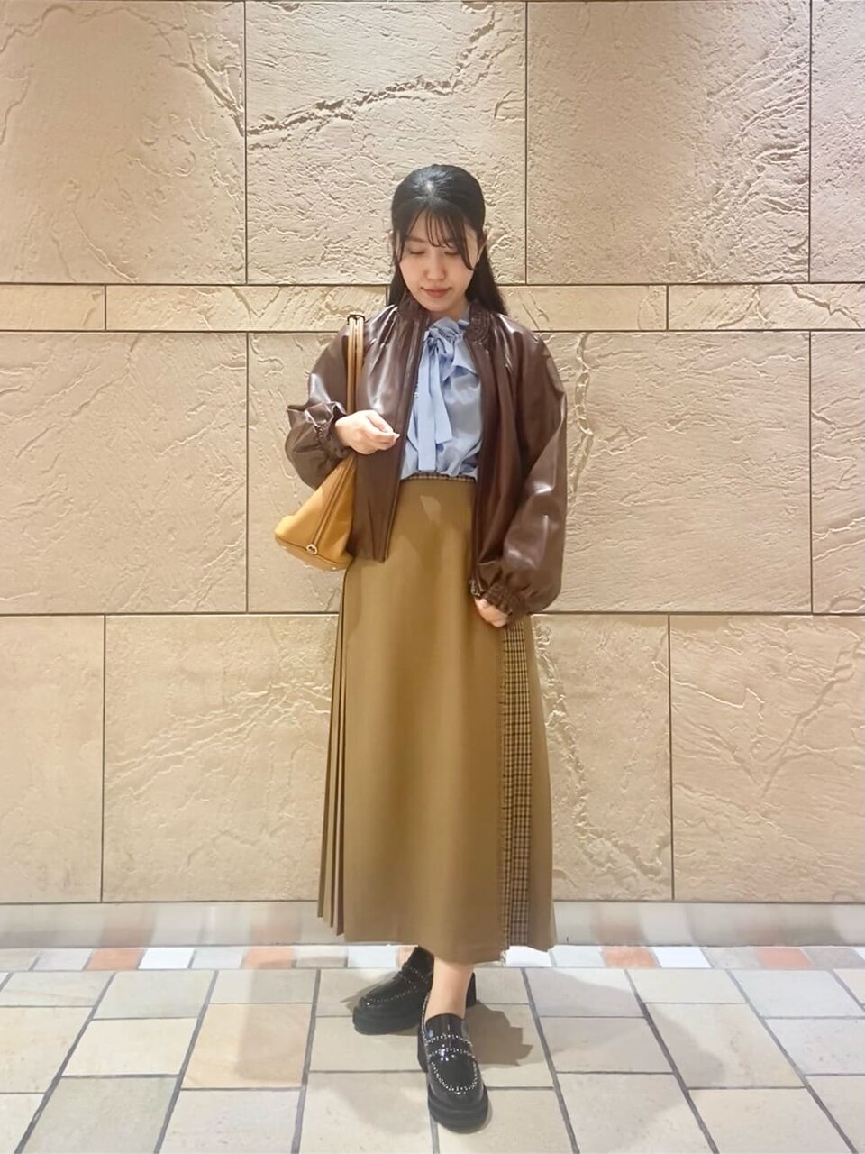 レザージャケットにコンビスカートをあわせた女性