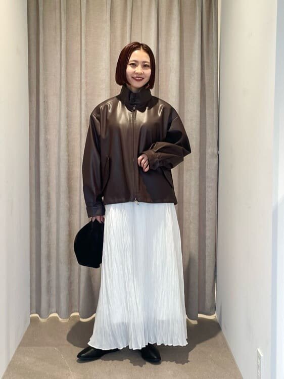 レザージャケットにプリーツスカートをあわせた女性