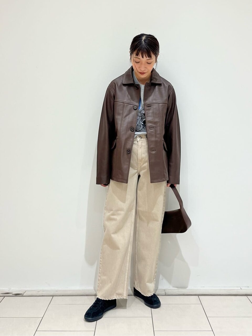 レザージャケットにデニムパンツをあわせた女性