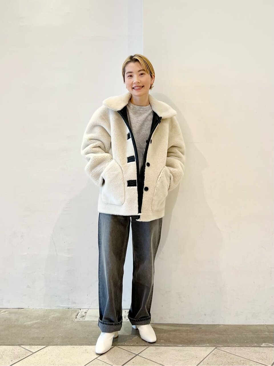 ホワイトのボアブルゾンとデニムを着用した女性