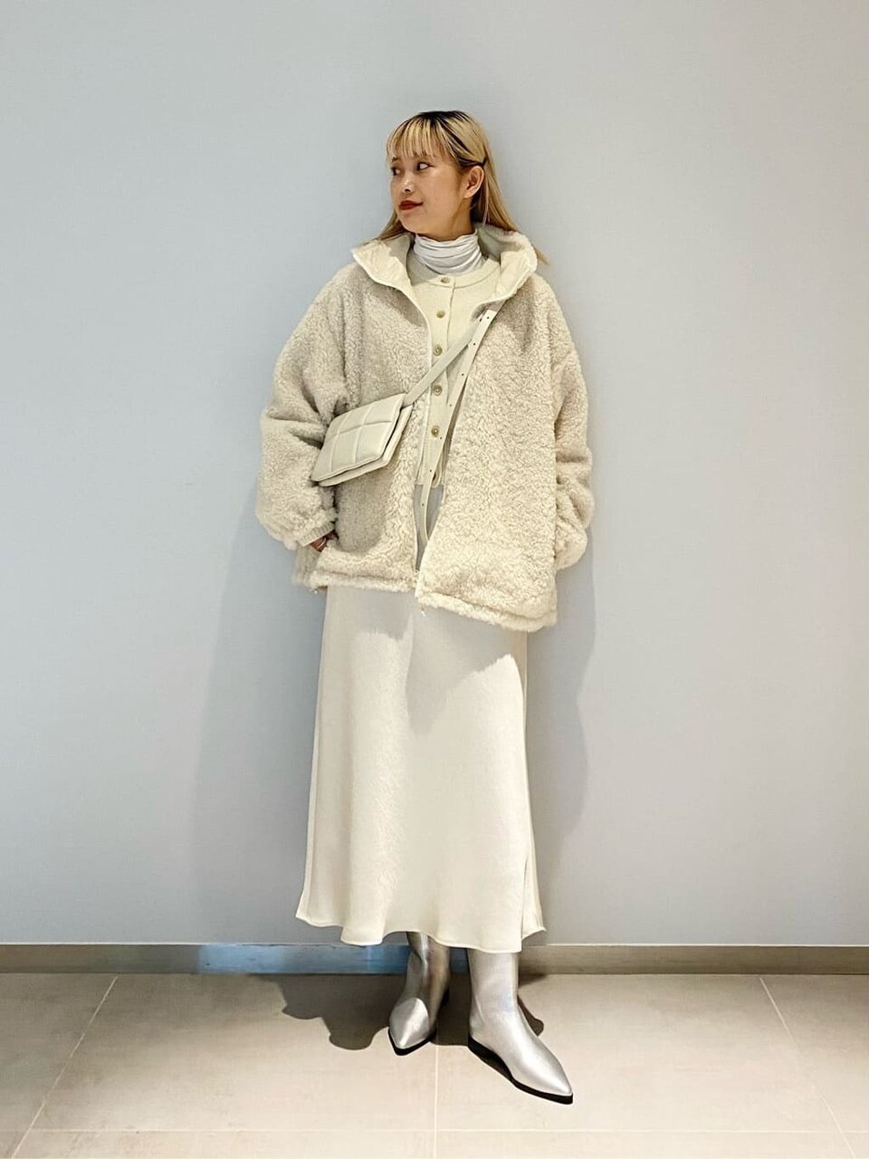 オフホワイトのボアブルゾン×マーメイドスカートを着用した女性