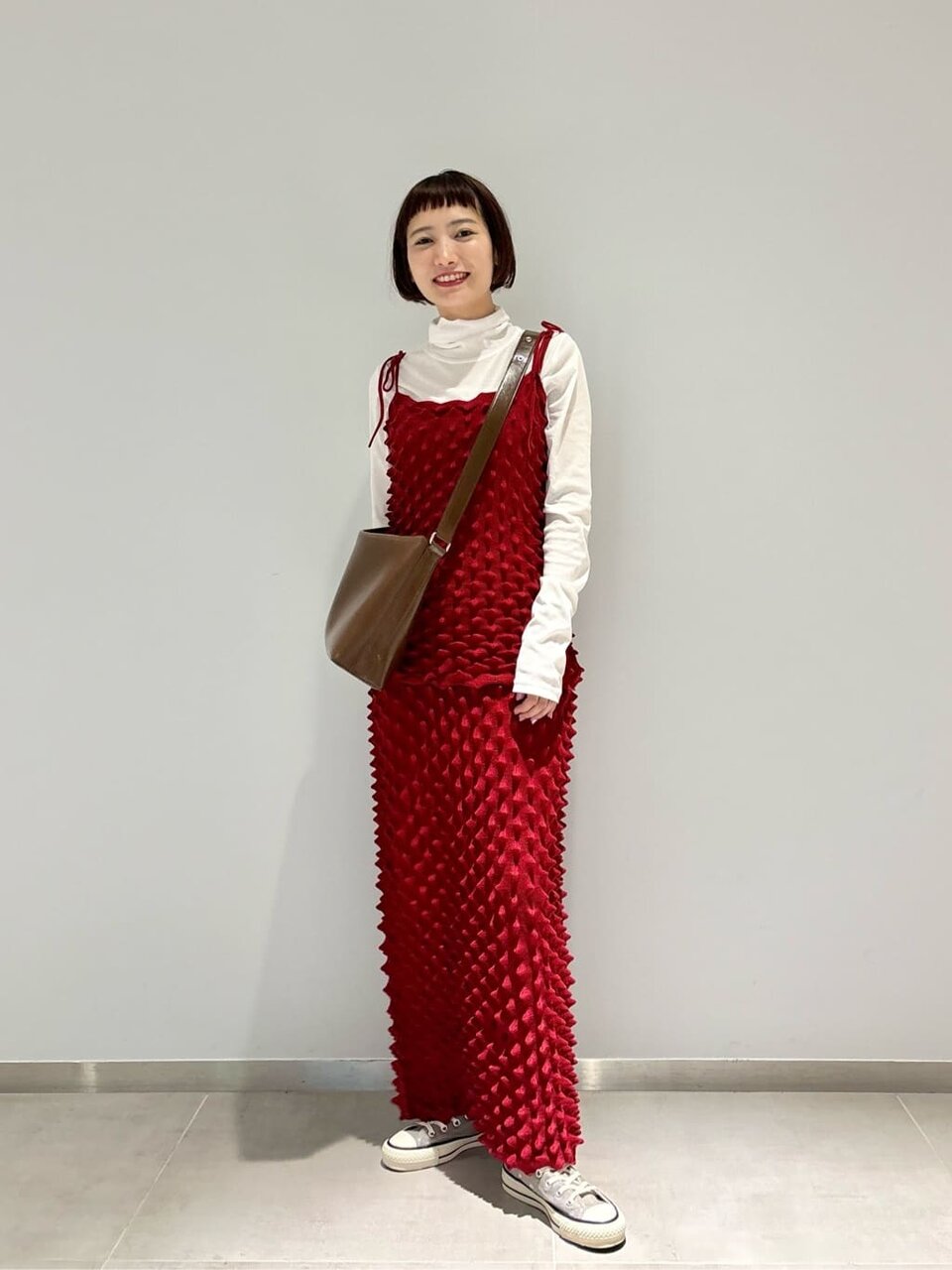 赤いニットとグレーのスカートを着た女性