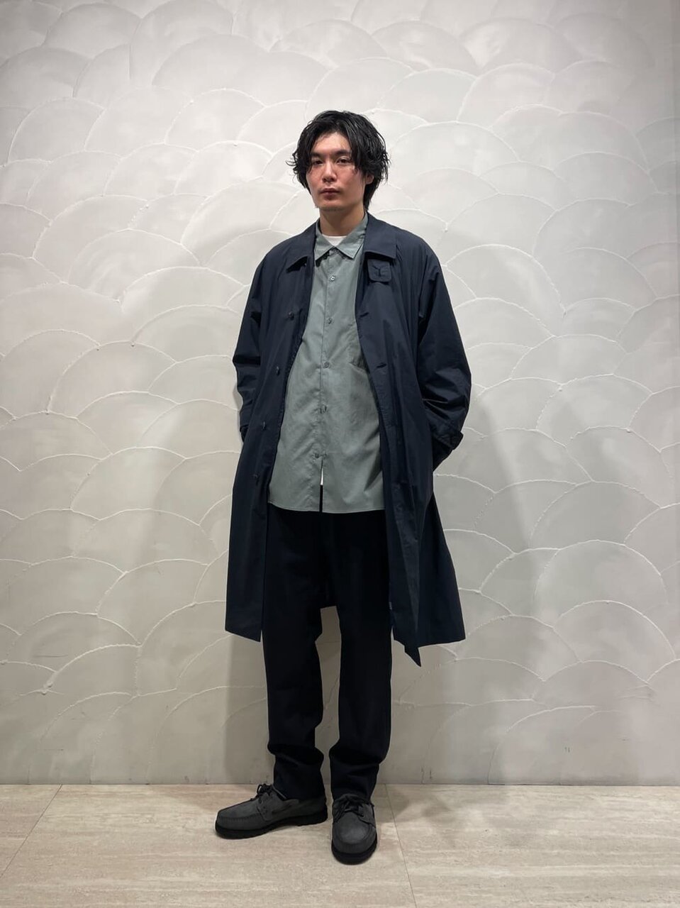 ステンカラーコートとシャツ、イージーパンツを着た男性