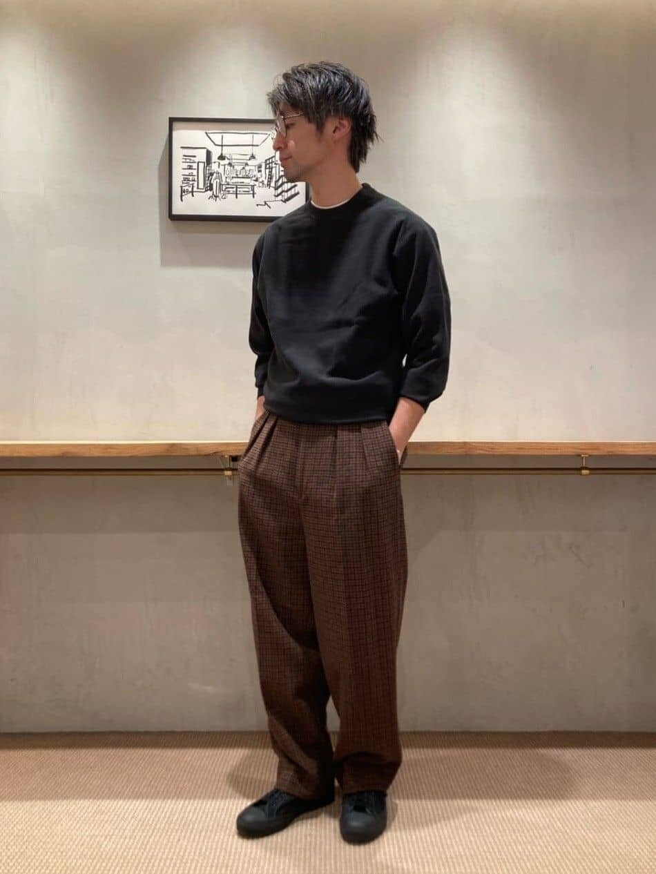 黒のスウェットと茶色のスラックスを着た男性