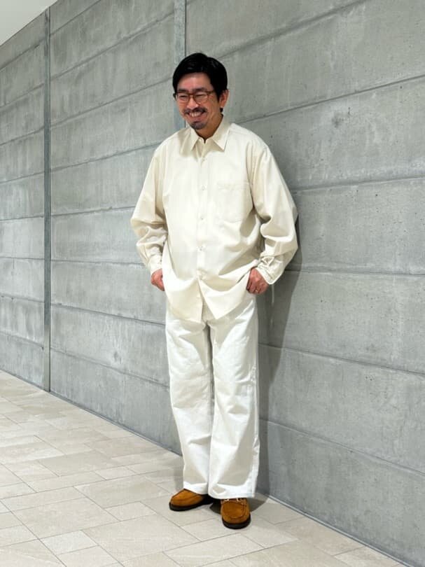 オフホワイトのシャツとパンツを着た男性
