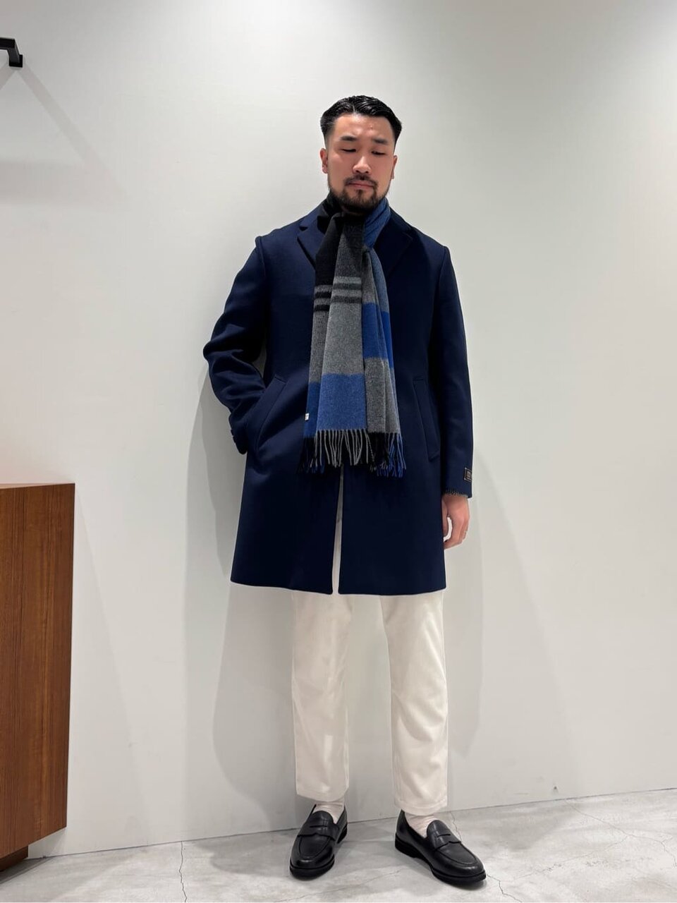 チェスターコートと白のコーデュロイパンツを着た男性