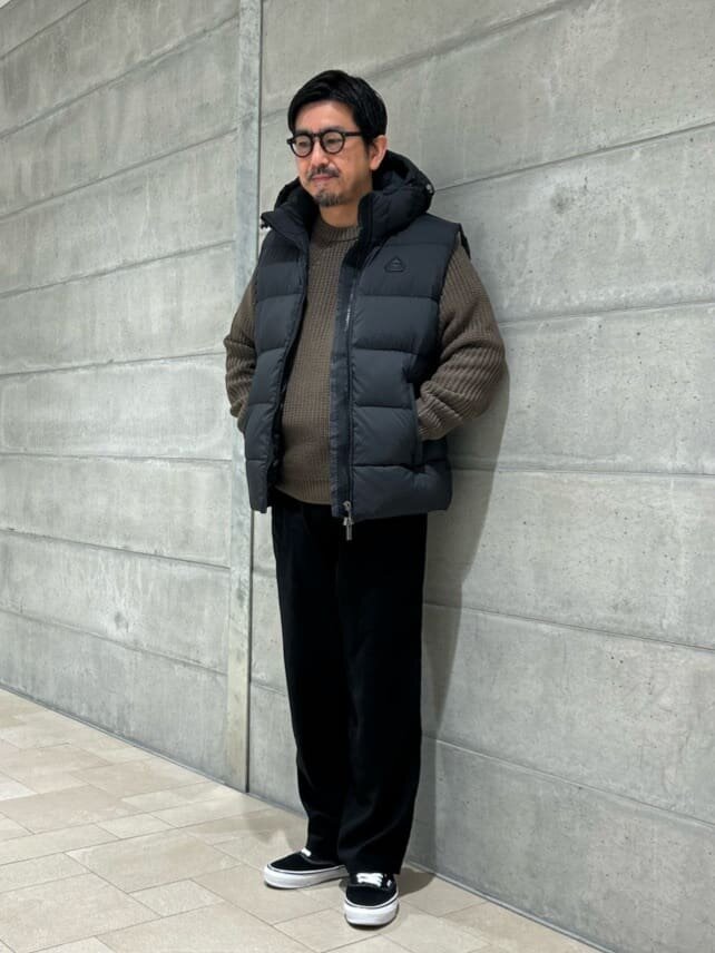 ダウンベストと黒のパンツを着た男性