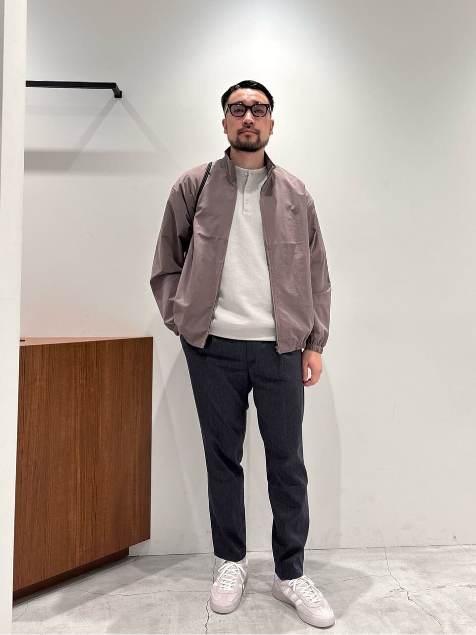 スタンドカラーブルゾンとテーパードパンツを着た男性