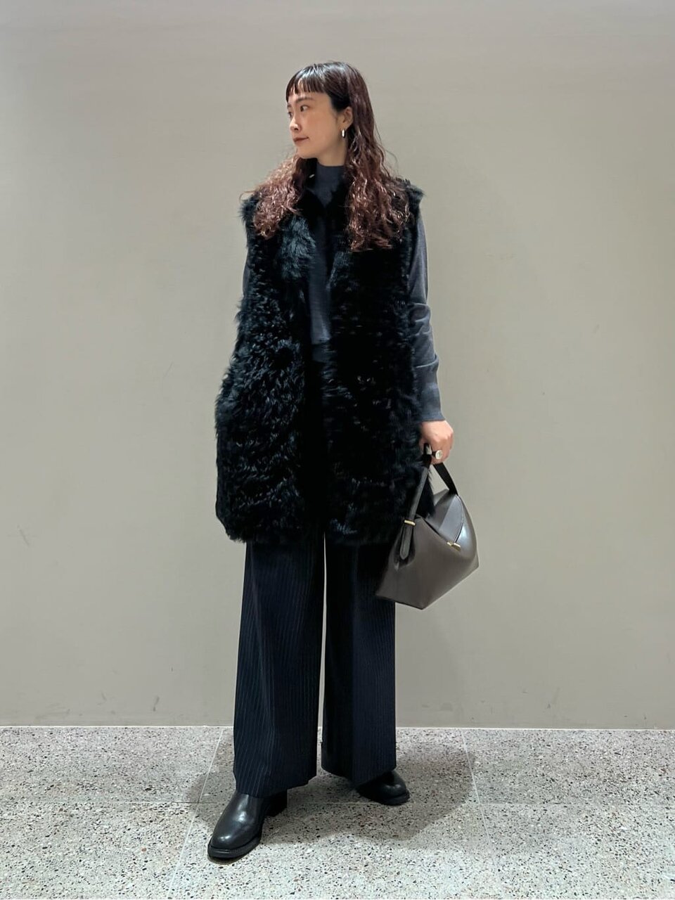 ファーのロングジレとワイドパンツを着た女性