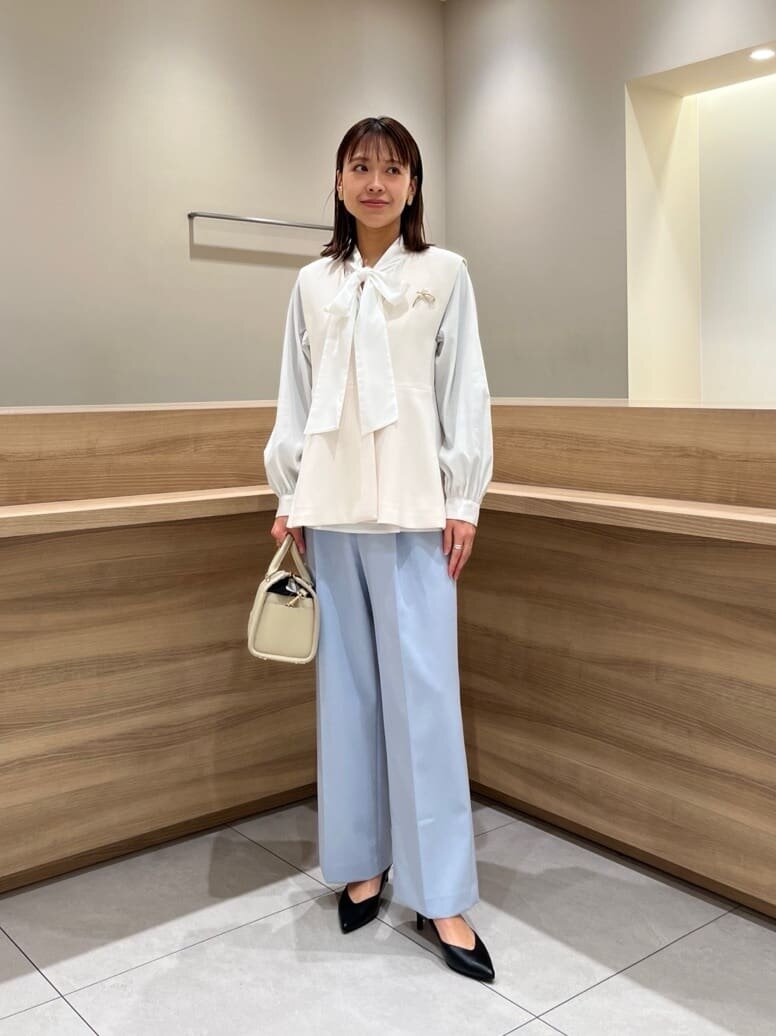 ジレと水色のパンツを着た女性